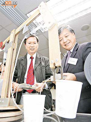 盧覺強（左）指透過針筒及氣壓教授如何製作機械臂，較為便宜及易明。	（陸智豪攝）