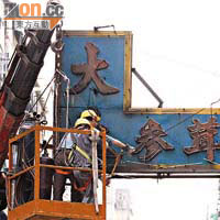 工人由吊臂協助清拆被燒至鬆脫的招牌。