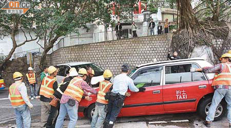 警員聯同多名修路工人合力把七人車推到路邊，以免交通受阻。	（蕭添榮攝）