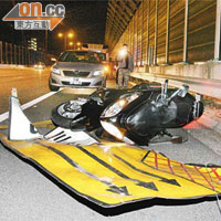 死者的電單車失控撞毀修路指示牌後橫亘路中。