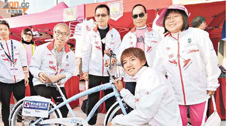 黃金寶（前）喺單車上簽名，胡經昌（後左起）、胡文新及許晉奎各自捐出二千元競投單車，再捐番單車出嚟投過。