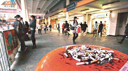 禁煙區範圍內的無煙灰缸垃圾桶上蓋堆滿煙蒂，滿布煙痕。