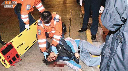 連環遭兩車猛撞的男子頭部重創，倒臥血泊中，由救護員急救。	（梁國雄攝）