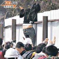 一名女示威者不顧危險，攀上支架。