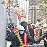 保安員開始施工焊接圍板，由人鏈前後保護。