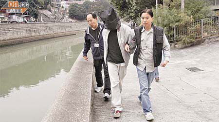 涉案男子由探員押往林村河邊調查。	（蔡楚華攝）