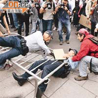 社民連示威者到達政府總部後與警方衝突，警員遭推倒被鐵馬壓着。