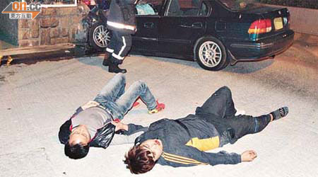 私家車失控撞壆，司機（左）及乘客受傷自行爬出車外候援。	（楊日權攝）