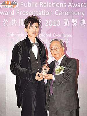 項明生（左）喺獎項籌委會主席陳祖澤手中捧下大獎。	（項明生提供）