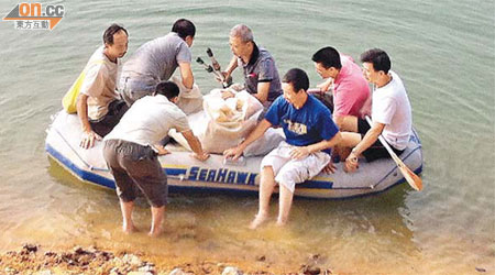 七名男子划橡皮艇到塘中捕魚。