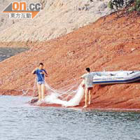 有市民不顧安危，乘橡皮艇到水塘中的小島落網捕魚。