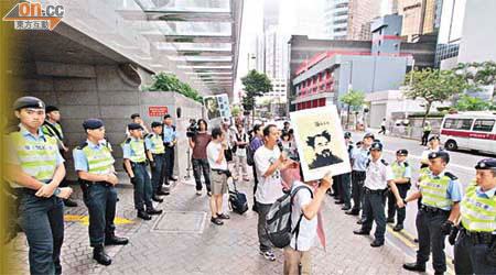 示威者在酒店高舉維權藝術家艾未未畫像，要求釋放艾未未，警員四層防線嚴密防守，不容許示威者接近王光亞。	（陳德賢攝）