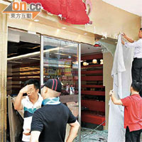 餐廳櫥窗玻璃及牆身遭歹徒駕車撞毀，職員忙於清理。	（林少兒攝）