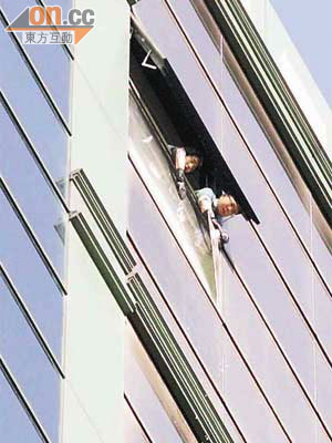 酒店職員清理爆裂玻璃幕牆的碎片。