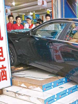 肇事寶馬房車撞爆手機店落地玻璃衝入店內，司機呆坐車內。（互聯網）