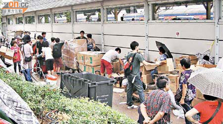 上水港鐵站外堆放大量冰皮月餅貨箱，一眾水貨客拆家在忙於拆貨及分貨。 