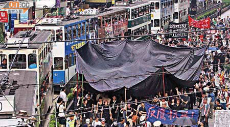 遊行人士高舉一塊八米乘二十米的巨型黑布，象徵港人正活在警方的極權黑影下。	（林少權攝）