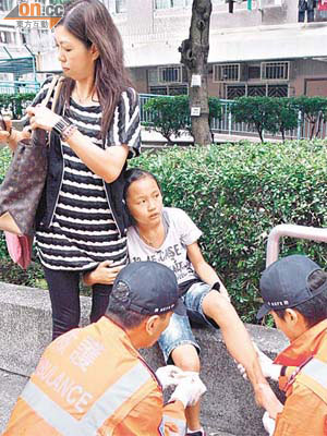 女童左腳受傷，攬着母親接受救護員敷治。	（曾紹良攝）