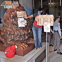 女長毛雷玉蓮在滙豐獅子銅像貼上不要強積金的標語。