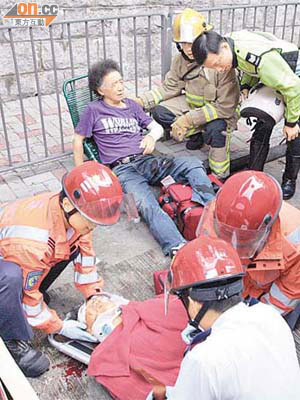 被巴士撞倒的小巴司機（後）及男途人（左），由消防員及救護員拯救。	（黃智康攝）
