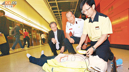 區偉民（右）示範用自動心臟除顫器為心臟停頓的乘客施救。左為黎清佳及沈國良（中）。（麥潤田攝）