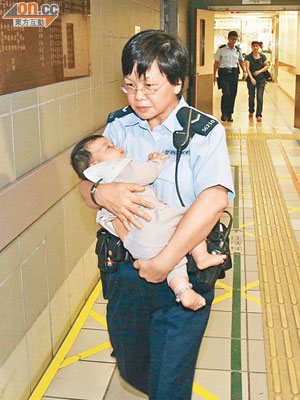 被狠母棄於麵店的女嬰，由女警抱往醫院檢查。（劉子文攝）