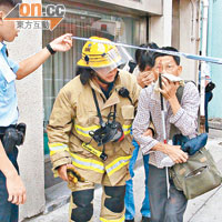 消防員帶領一名失明人士逃離現場。
