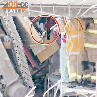 被困工人雙腳露出挖掘機駕駛室外（圓圈示），消防員進行拯救。 