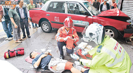 救護員為受傷途人包紮，肇事的士撞向鐵閘損毀。（左錦鴻攝）