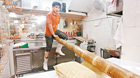 坤記竹昇麵打麵師傅以傳統竹昇壓麵方法製作麵條。（林少權攝）
