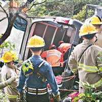 肇事客貨車剷落卅公尺深山坡下翻側，消防員揭開車尾救人。
