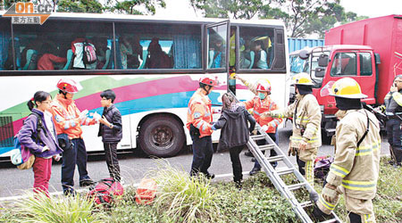 消防員用鋼梯協助受傷學生爬出旅遊巴士。（梁卓明攝）