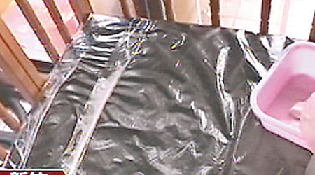 警方在疑犯住處發現用黑色膠袋覆蓋的嬰兒床。（電視畫面）