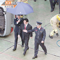 陳智敏在一名消防高官擔遮擋雨下，由消防處處長陳楚鑫陪伴前往參觀。