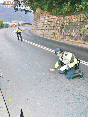 交通警員在司徒拔道奪命車禍現場調查，路中遺下電單車碎片。（劉展超攝）