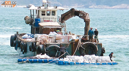 載滿一包包水泥的躉船於近岸「卸貨」到浮台上。（大浪灣之友提供）
