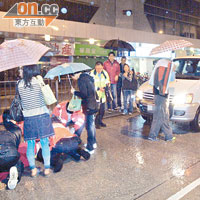 數名熱心途人為女傷者打傘擋雨。