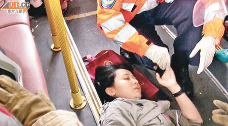 受傷女乘客倒臥巴士下層，救護員為她檢查。（曾志恒攝）