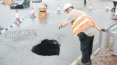 路政署人員檢查路面深洞時，一手扶着路欄以策安全。（劉展超攝）