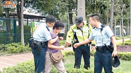 警員阻止婦人食草及勸喻她將雜草吐出。（李子強攝）