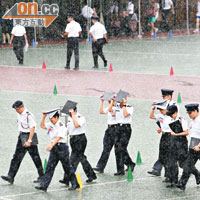 練習中途下起滂沱大雨，場中央的隊員急步到有瓦遮頭地方避雨。