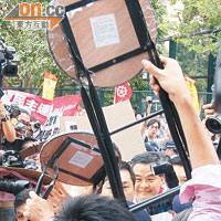 進場 舉摺櫈<br>有示威者企圖向梁振英送上摺櫈，現場險象環生。