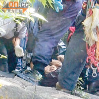 搜救人員將另一名赤裸上身男子的屍體抬上潭邊岩石。