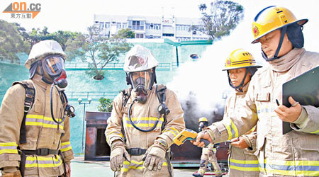 數名消防員昨在八鄉消防訓練學校示範室內煙火特性訓練，示範完結後，消防員雙手無恙。（陳錦輝攝）