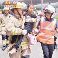 消防員抱起受傷女童送上救護車。