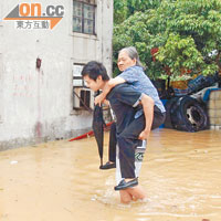 流浮山輞井村被洪水圍困，有村民孭長者疏散。（黃君堡攝）