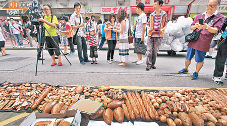 團體將一間超市棄置的二百多個麵包及蔬菜擺放在街頭。（蕭毅攝）