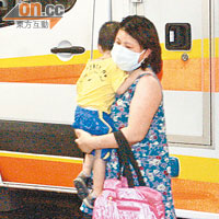被毆婦人抱着幼子到醫院。（李豪杰攝）