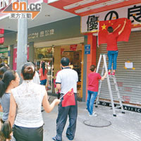 有港資商店為免被示威者誤會破壞，在店外貼告示及掛國旗。（本報東莞傳真）