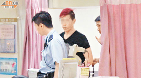 頭髮染成紅色的疑犯由警員押往醫院治療。（麥少峰攝）